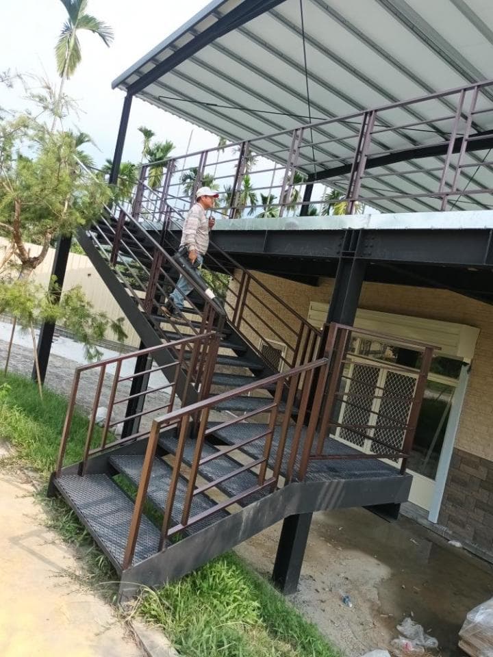 這張「鐵製樓梯」的照片是一座通往二樓的樓梯,樓梯有扶手,看起來很堅固,底下是水泥地。