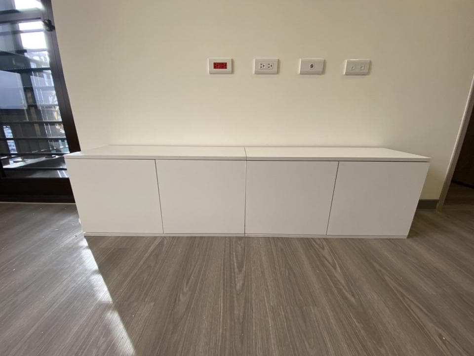 這張照片是一張白色櫃子,櫃子有三個門,分成兩排,每排各有兩個門。櫃子底下是木紋地板。