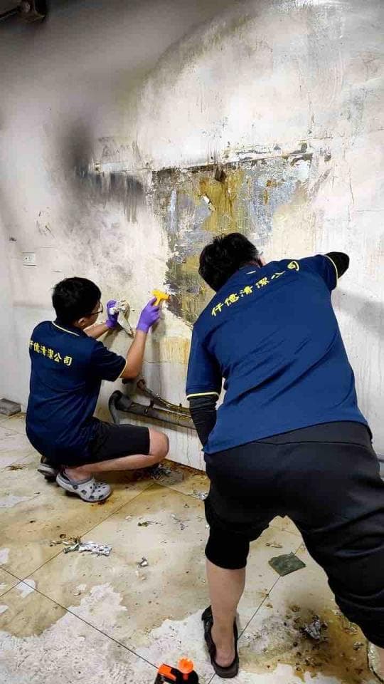 1) 照片顯示兩名男子在牆壁上做清潔工作,牆壁上有一部分已經被清理掉了,可以看到部分牆壁的顏色與原本的顏色不同