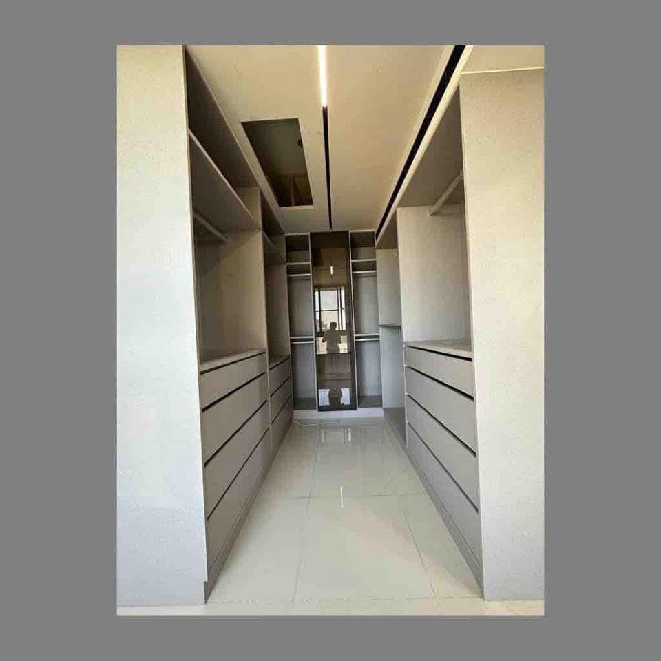 這張照片是一個大型衣帽間,房間中央是寬敞的走道,兩旁是整排的衣櫃和抽屜,看起來十分寬敞明亮。