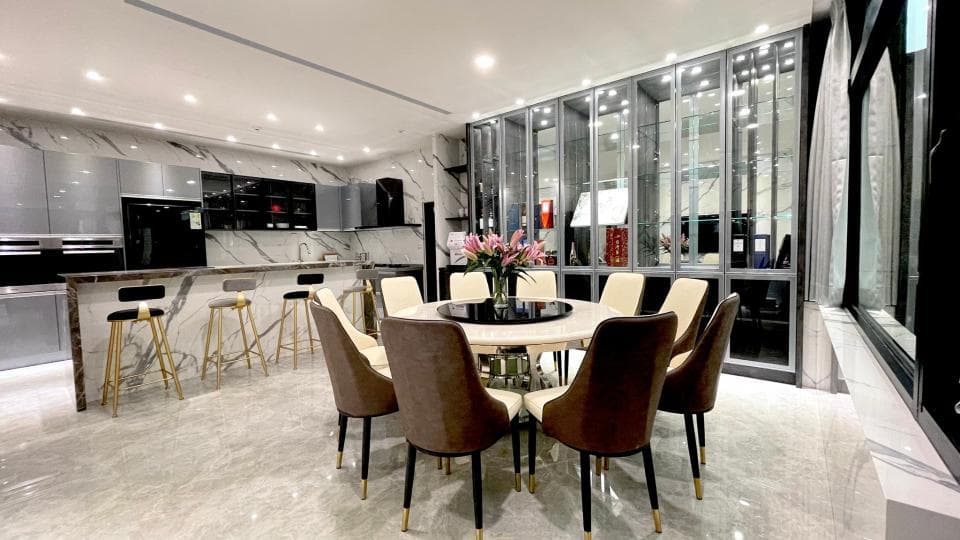 這張照片是一間現代化的廚房和餐廳,其中最引人注目的是中間的餐桌,上面擺放著一個精美的花瓶,裡面插滿了鮮豔的花朵,營造出溫馨而優雅的氛圍。