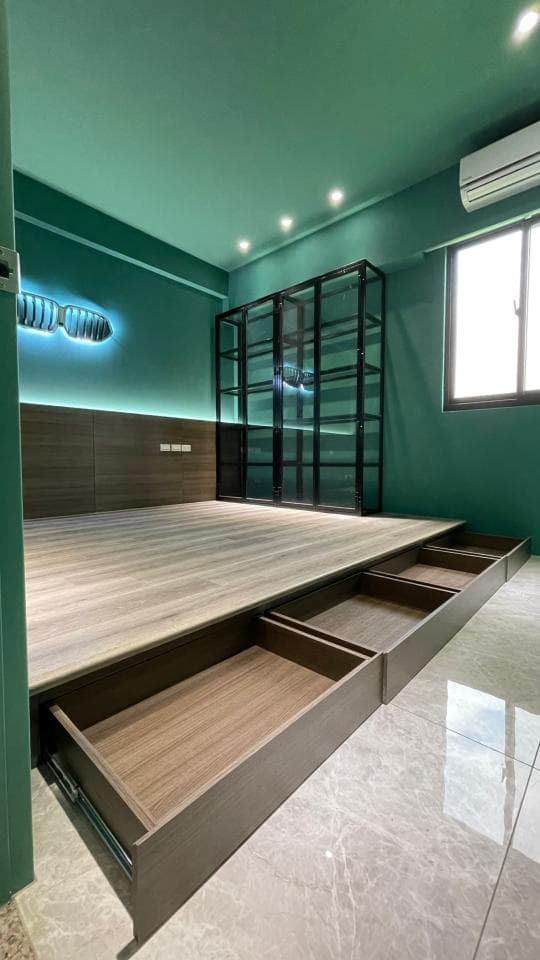 1) 照片顯示一個綠色牆壁的房間,房間裡有一個木地板平台,平台上有一個黑色金屬架子,以及三個木製抽屜