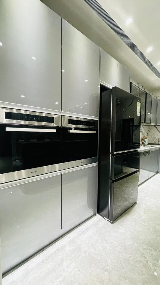 這張照片是一個現代化的廚房,最重要的是嵌入式烤箱和冰箱,它們都是黑色的,烤箱上有銀色的把手,冰箱有兩個門,上面是黑色的,下面是銀色的。