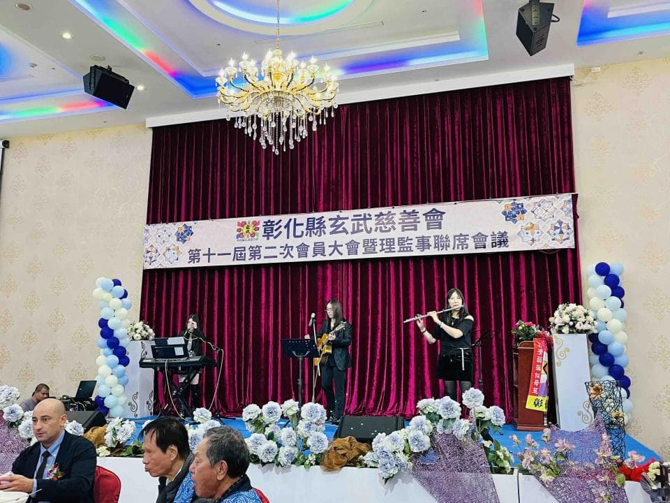 這張照片是第十一屆第二次會員大會暨理監事聯席會議的現場。舞台上,一位女士正在演奏長笛。