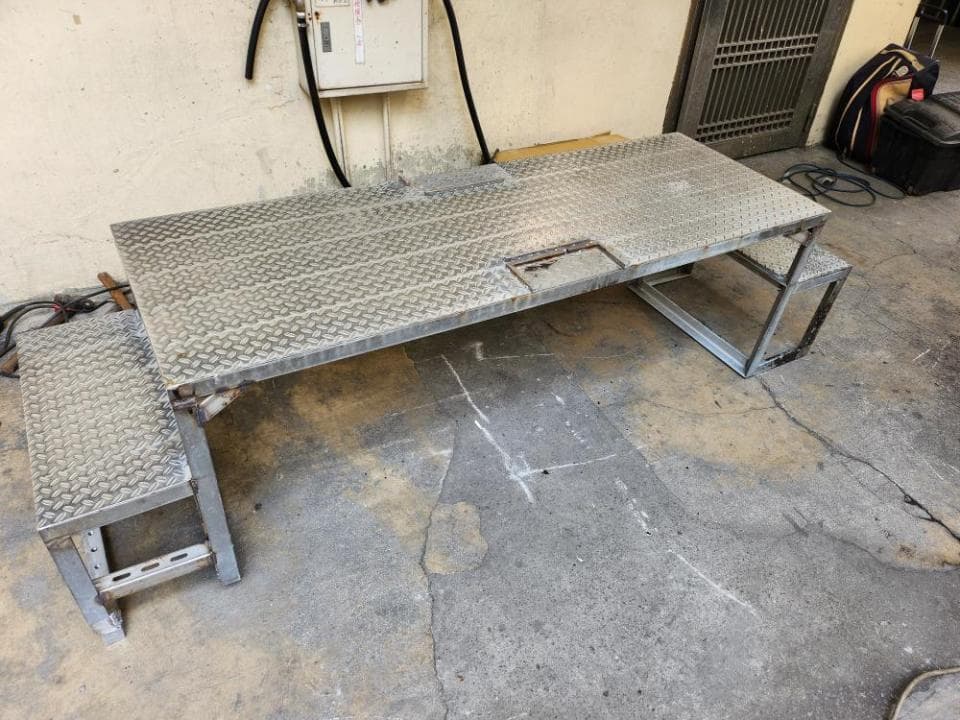 1) 這張照片顯示了一個金屬製的長方形桌子,桌子上有鑽孔,桌子上有兩個長方形的台子