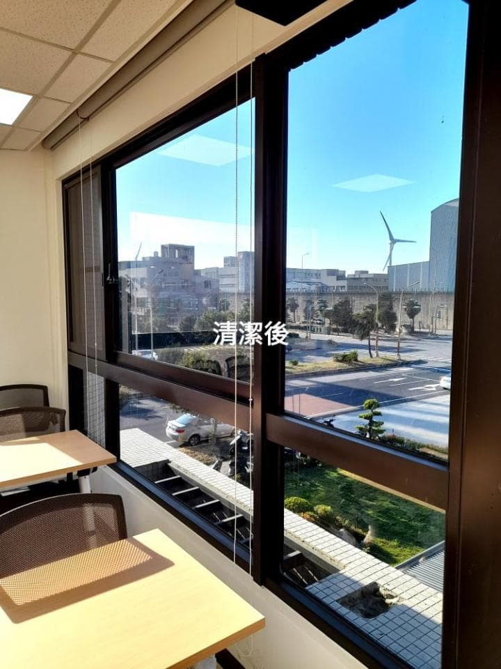 1) 照片顯示一個房間,房間裡有兩張桌子和椅子,窗戶外可以看到遠處的建築物和草地