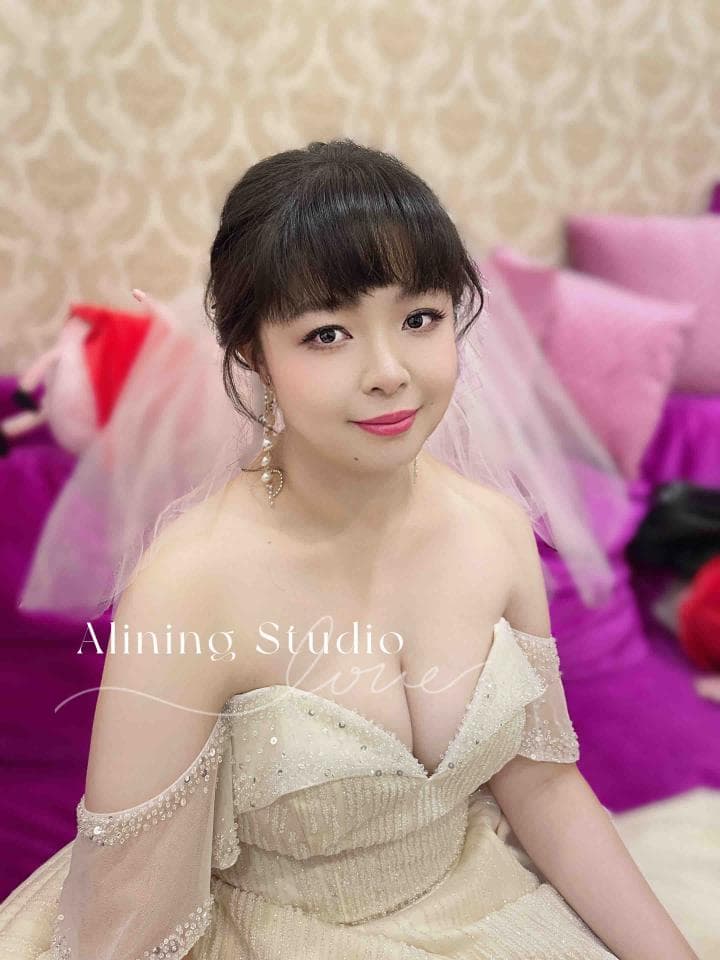 這張照片是一個穿著白色婚紗的新娘,她正對著鏡頭微笑,她頭上戴著粉色頭紗,臉上化著精緻的妝容,看起來非常美麗動人。