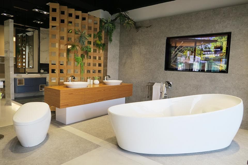 這張照片是一個現代化的浴室,其中最重要的是一個白色橢圓形的浴缸。 浴缸位於右邊,並有一個木質的櫃台和兩個洗手盆。 牆壁是灰色的,有一個大的鏡子,可以反射浴室的周圍環境。