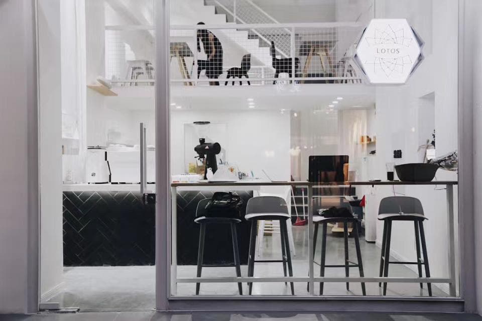 這張「咖啡廳」的照片是,一張玻璃門,可以看到店裡的吧檯,還有白色的桌椅和一個黑色的櫃子,櫃子上方有一個標誌寫著「COTTON HOUSE」。