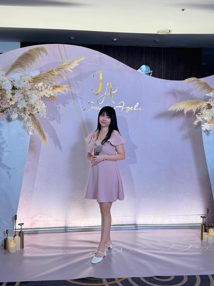 這張「婚禮」的照片是一個穿著粉色洋裝的女性站在婚禮佈置前面。