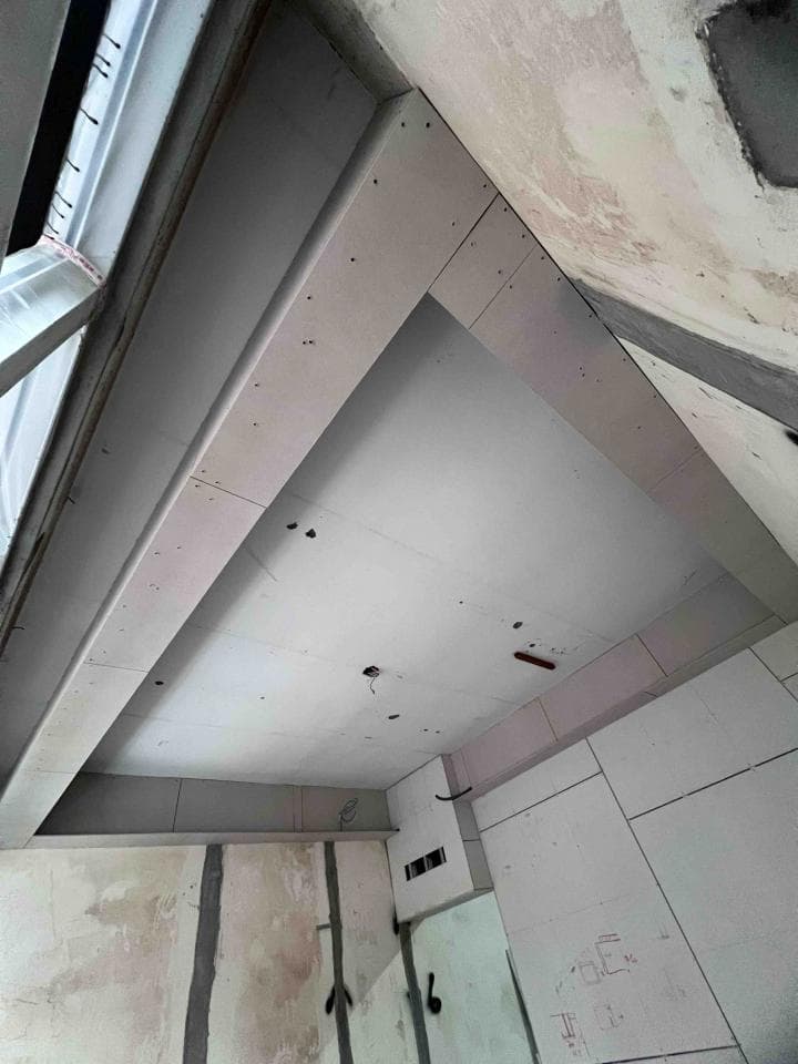 這張照片是一間正在裝修的房間,最重要的是房間的天花板,它採用了複雜的設計,由多個白色板材拼接而成,形成了多個層次。