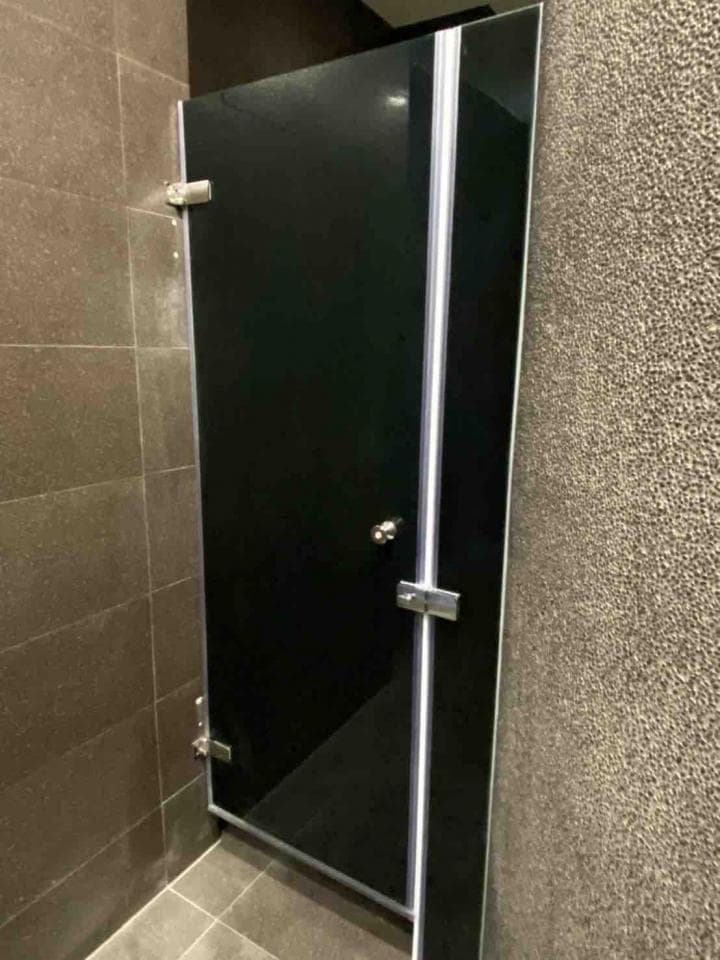 這張照片是一個浴室的黑色玻璃門,門上有銀色的把手和鉸鏈。