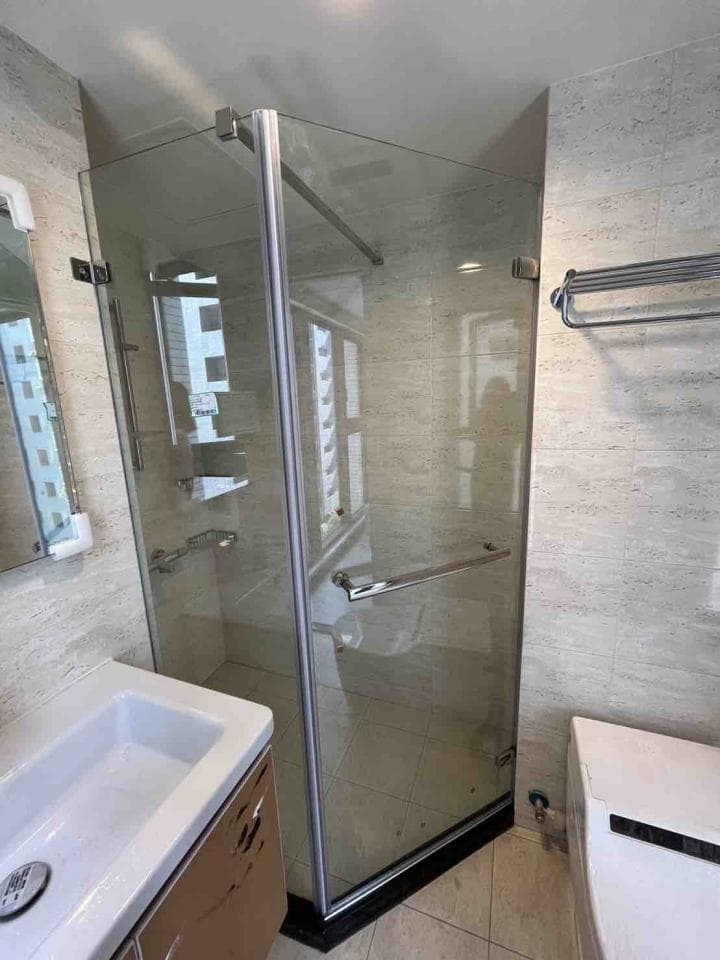 這張照片是一個現代化的浴室,最重要的是淋浴間的設計。淋浴間採用透明玻璃,給人乾淨明亮的感覺,而且配備了簡約的銀色金屬把手和架子,提升整體的質感。