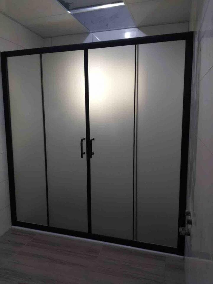 這張照片是一個現代化的浴室,主要特徵是黑框玻璃門,看起來時尚且簡潔。