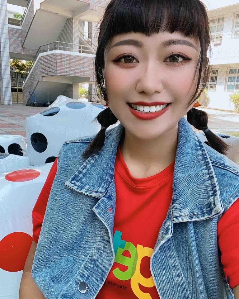 這張照片是一個年輕女子,她穿著一件紅色T恤,上面印著彩色字體,並穿著一件牛仔外套。