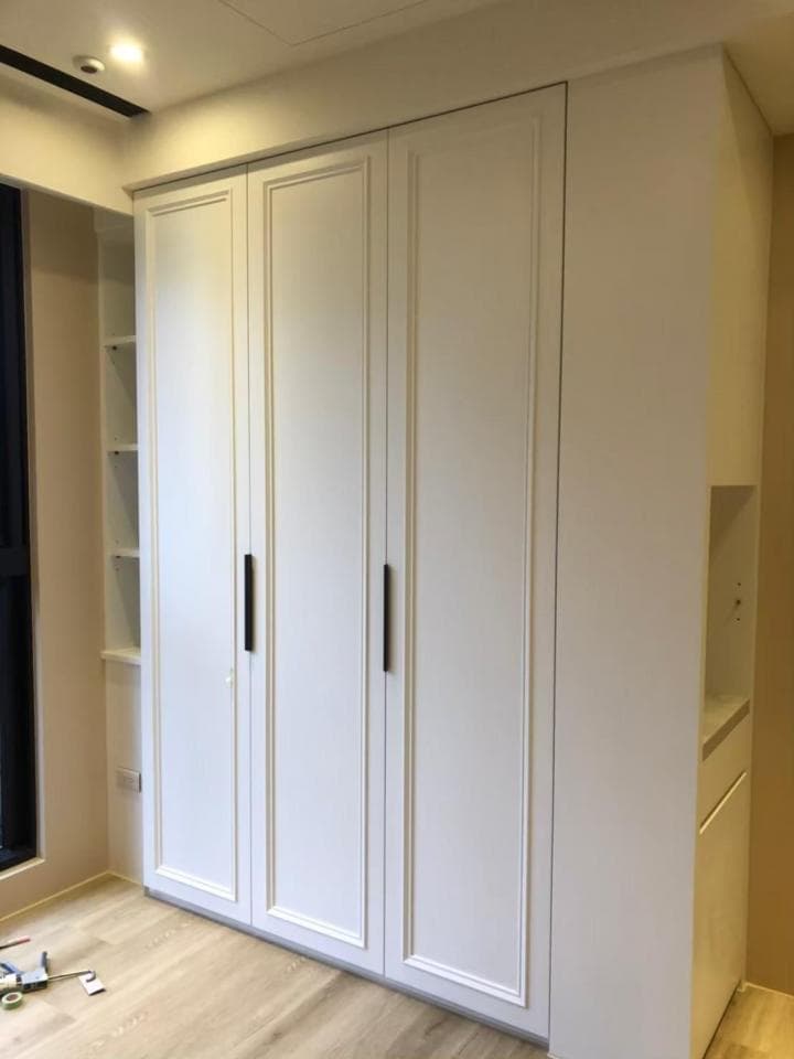 1) 照片顯示一個白色的衣櫃,有三個櫃門和一個抽屜