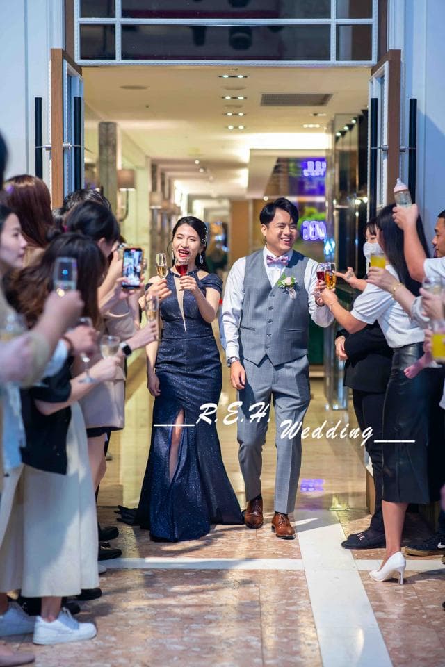 這張照片是一對新人在婚禮上舉杯敬酒,他們穿著正式的服裝,男方穿著西裝,女方穿著婚紗,笑容滿面,看起來非常幸福。