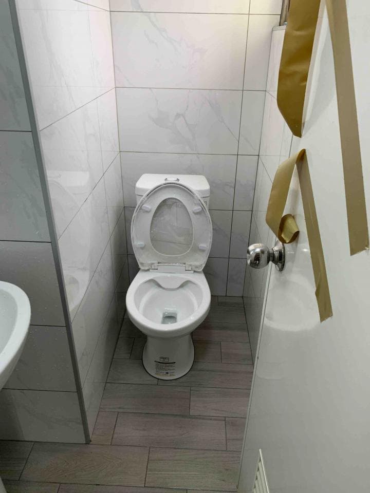 這張照片是一個浴室,最重要的是馬桶。馬桶是白色的,有蓋子,看起來很乾淨。