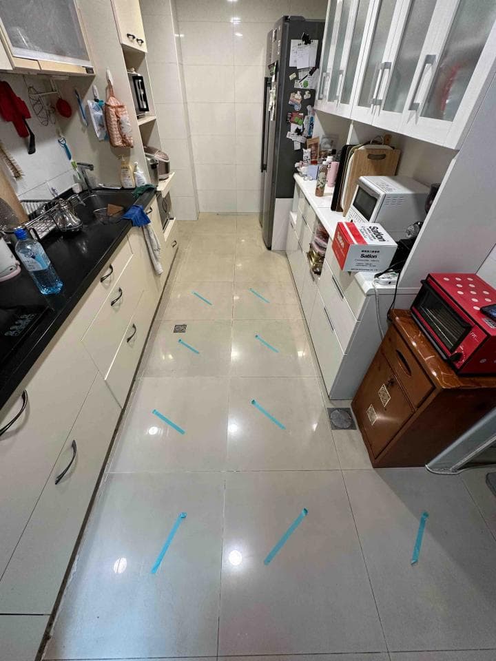 這張照片是一個廚房,地上有藍色的膠帶,標示著安全行走路線。