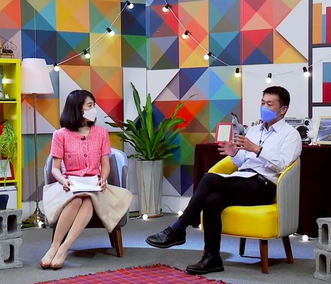 這張「訪談」的照片是兩個人,一個女人和一個男人,他們坐在椅子上,戴著口罩,正在交談。