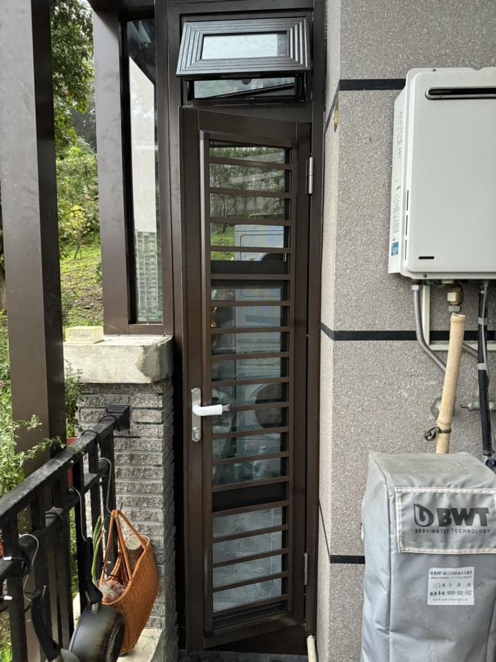 這張照片是一扇帶有格柵的玻璃門,門上有個小窗戶,窗戶是開着的,門上還有一個白色的把手。