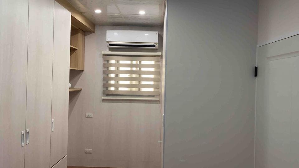 1) 照片顯示一個房間的角落,有一個白色木門的牆壁,房間的牆壁是乳白色的,左邊的牆上有兩扇白色木門的衣櫃,衣櫃的門上各有一個門把