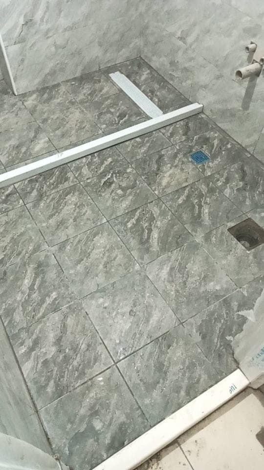 這張照片是一間浴室,其中最重要的部分是浴室地板上鋪的灰色瓷磚。瓷磚上有明顯的紋理,看起來像石頭。