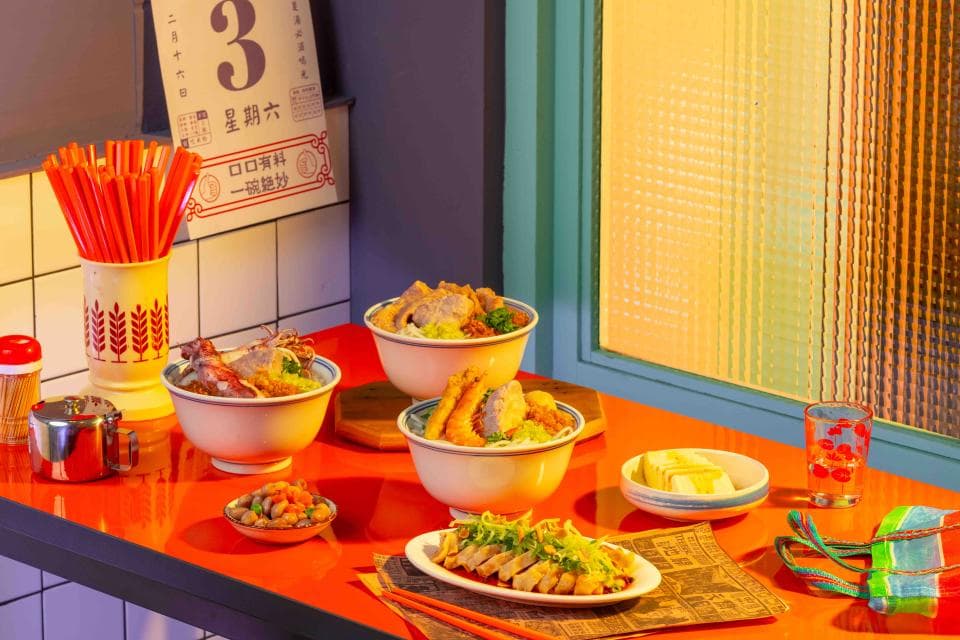 這張「食物」的照片是三碗不同種類的麵食,搭配著一些小菜,擺放在橘色的桌子上。