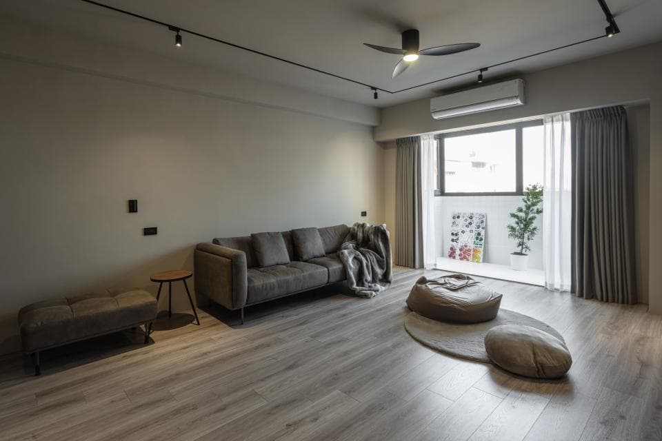 1) 照片顯示一個現代風格的客廳,有一張灰色沙發、一個木頭咖啡桌、一個灰色長凳和兩個灰色坐墊