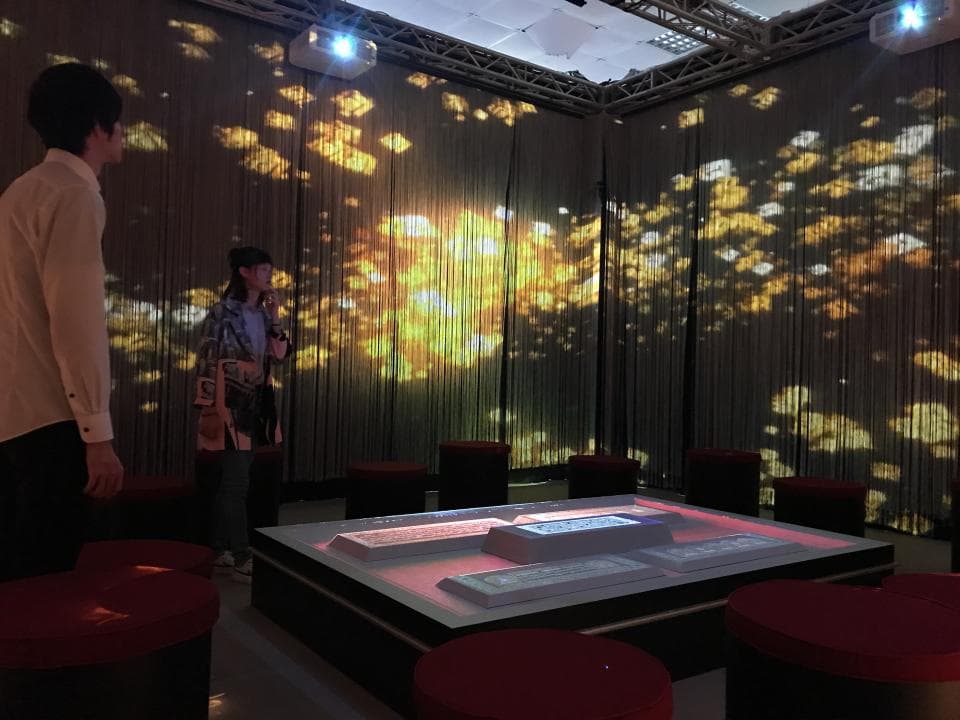 這張「室內裝飾」的照片是一個裝飾著金色圖案的房間,裡面有兩個穿著休閒服裝的人和一個玻璃桌,桌上放著燈光。