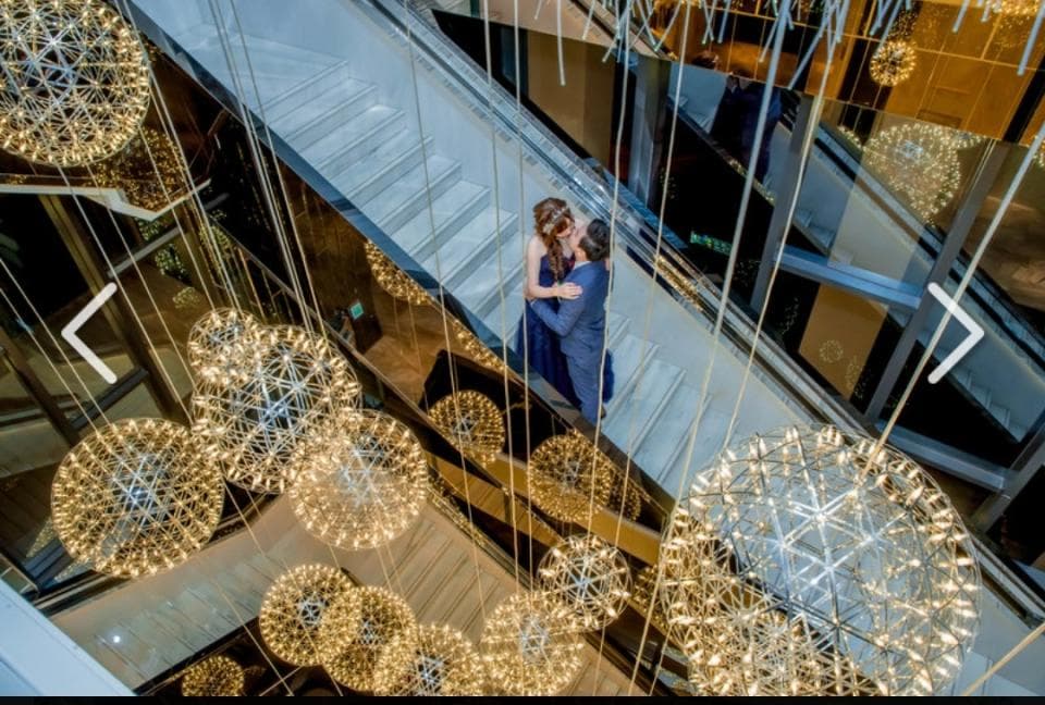 這張「一對情侶在樓梯間擁抱」的照片是,他們站在現代化的樓梯間,背景是華麗的燈飾。