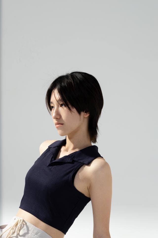 這張照片是一個年輕女子穿著黑色無袖上衣的半身照。