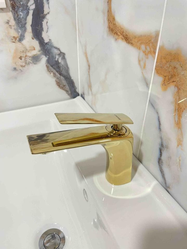 這張照片是一個帶有金色水龍頭的白色陶瓷洗臉盆。