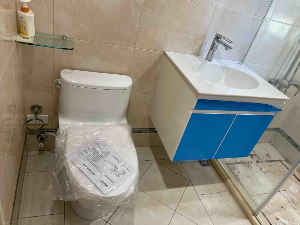 這張照片是一個現代化的浴室,最重要的是一個藍色櫃子,上面有一個白色的洗手台和一個銀色的水龍頭。