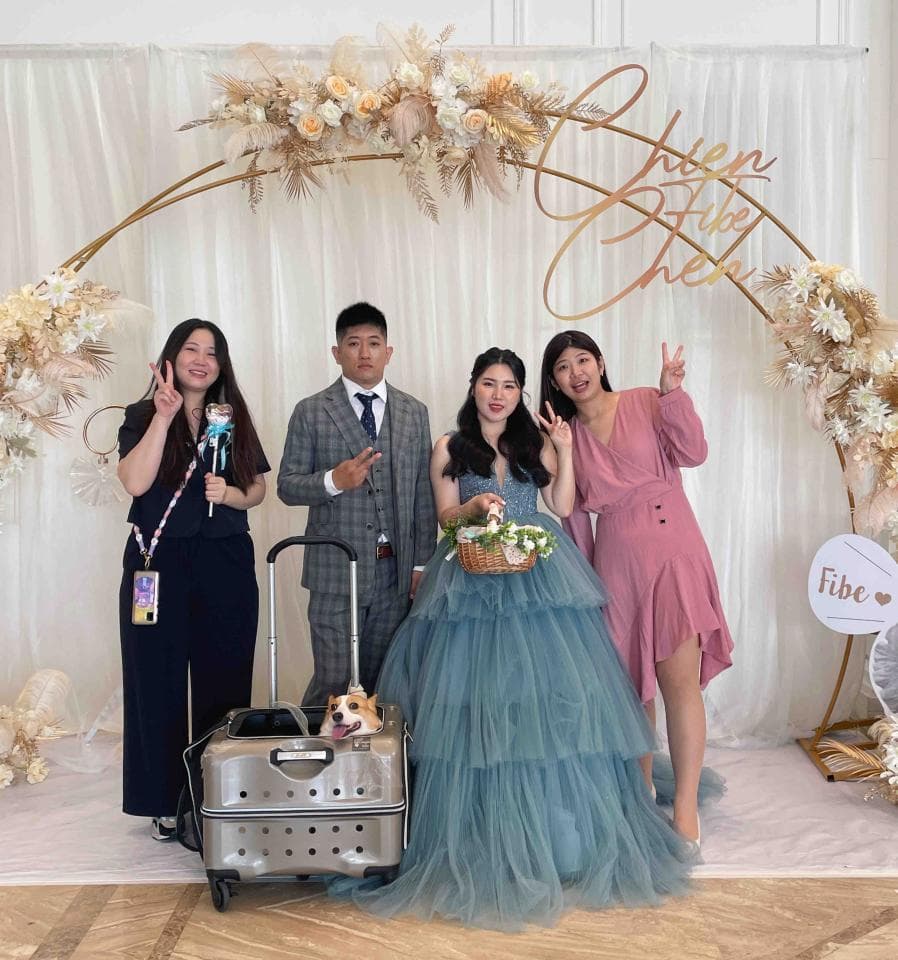 這張「婚禮」的照片是四個人在花拱門前拍照,其中一位穿著藍色禮服的女生手拿捧花,另外三個人站在她旁邊。