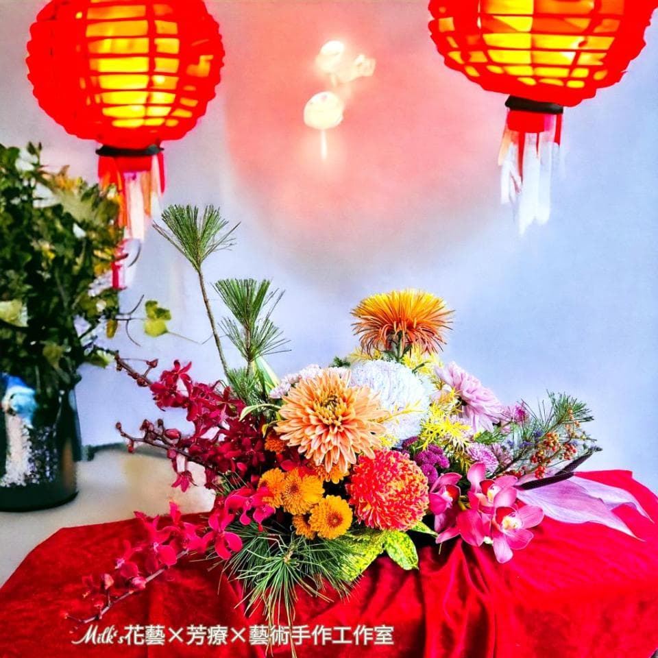 1) 照片中有一束鮮花放在紅色的桌布上,花束由多種花卉組成,包括粉色蘭花、橙色菊花、黃色菊花、紅色玫瑰等