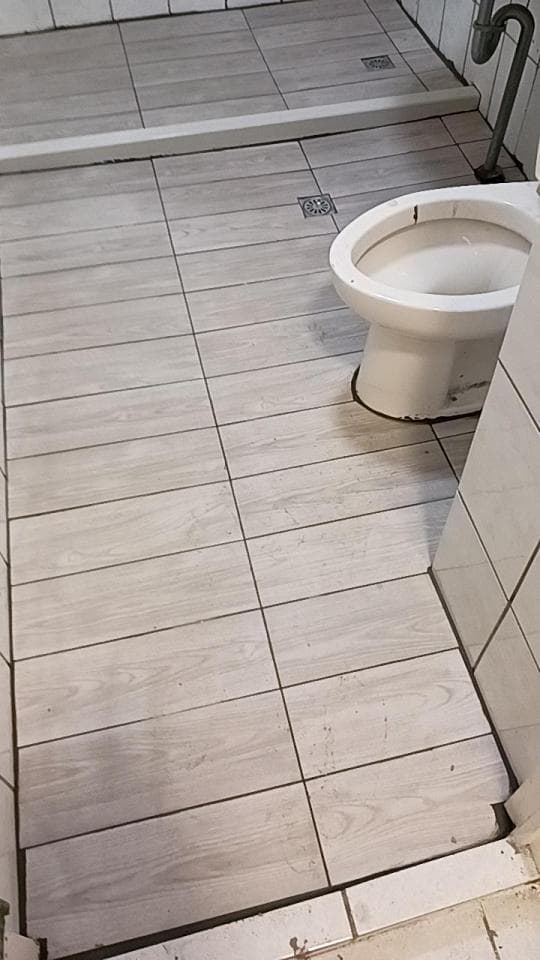 這張照片是一間浴室的地板,地板上鋪著木紋磁磚,看起來很乾淨整潔。