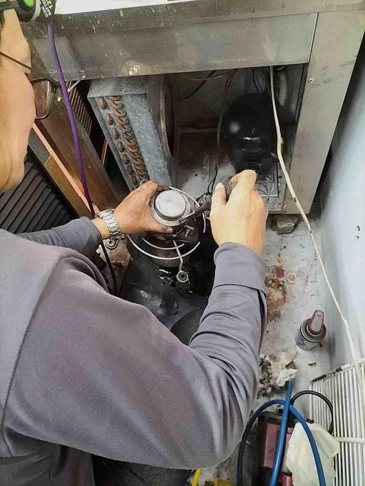 1) 照片顯示一個人在檢查空調室外機