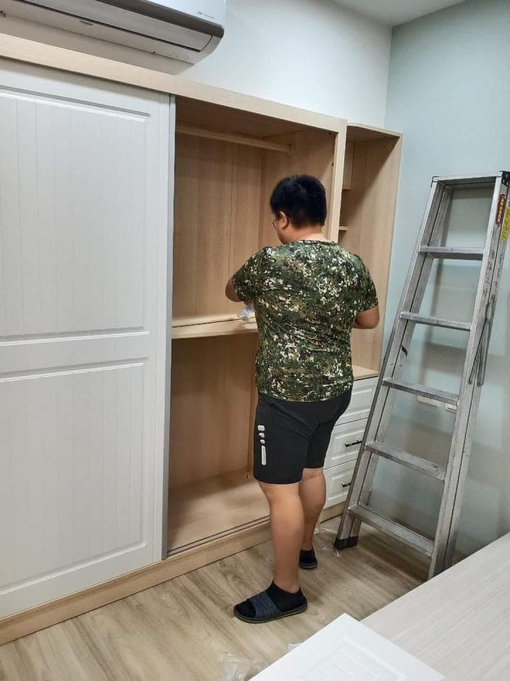 1) 照片顯示一名男子站在衣櫃前,正準備把木板放進衣櫃裡