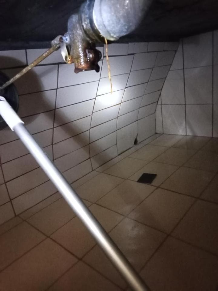 1) 照片顯示一個滴水的管道,在滴水的下方有瓷磚地板,地板上有污垢,照片中有個銀色的桿子