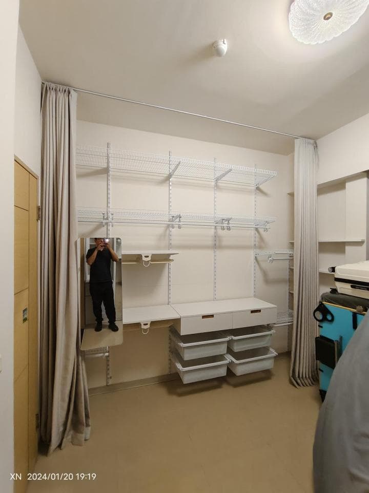 1) 照片顯示一個房間,房間裡有一個大型的白色衣櫃,衣櫃裡裝滿了架子和抽屜