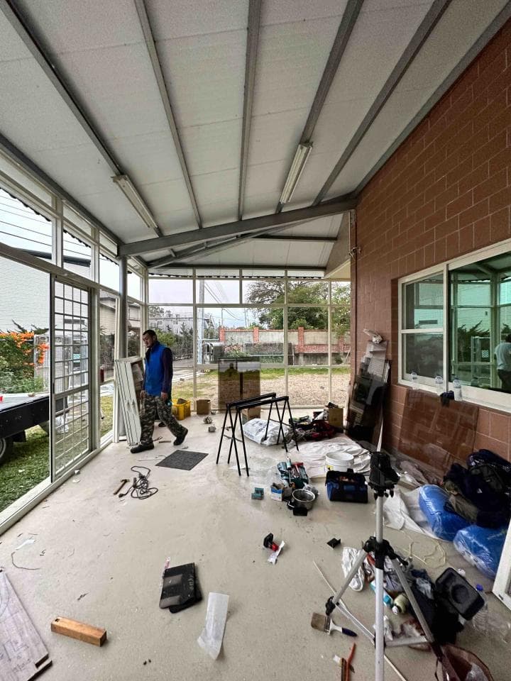 這張照片是一個正在施工的房屋,照片中有一個工人正在工作,周圍還有許多建築材料和工具。