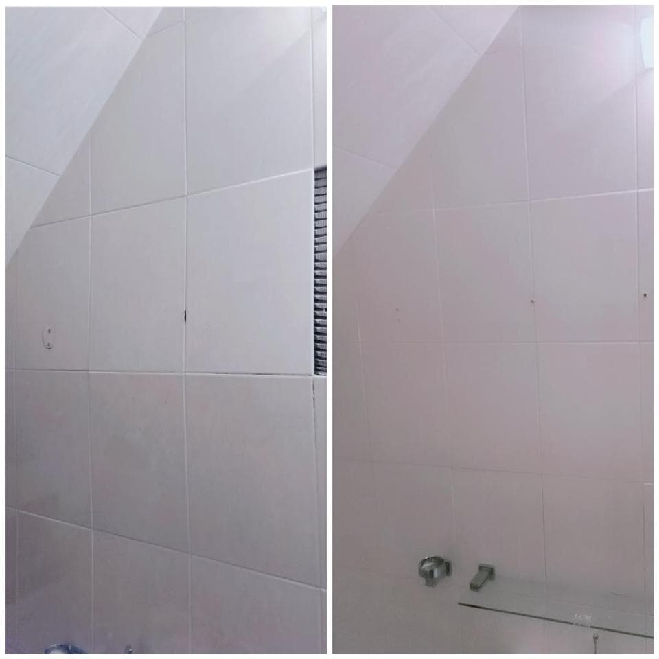 1. 照片顯示一個白色瓷磚牆面,左邊是比較完整的牆面,右邊是浴室的牆面,右邊牆面上有淋浴頭和一層白色瓷磚