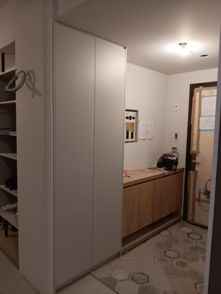 這張照片是一個現代化的走廊,最重要的是牆上的一個白色大櫃子,它佔據了牆壁的大部分空間,並有兩個門,看起來非常整潔且時尚。