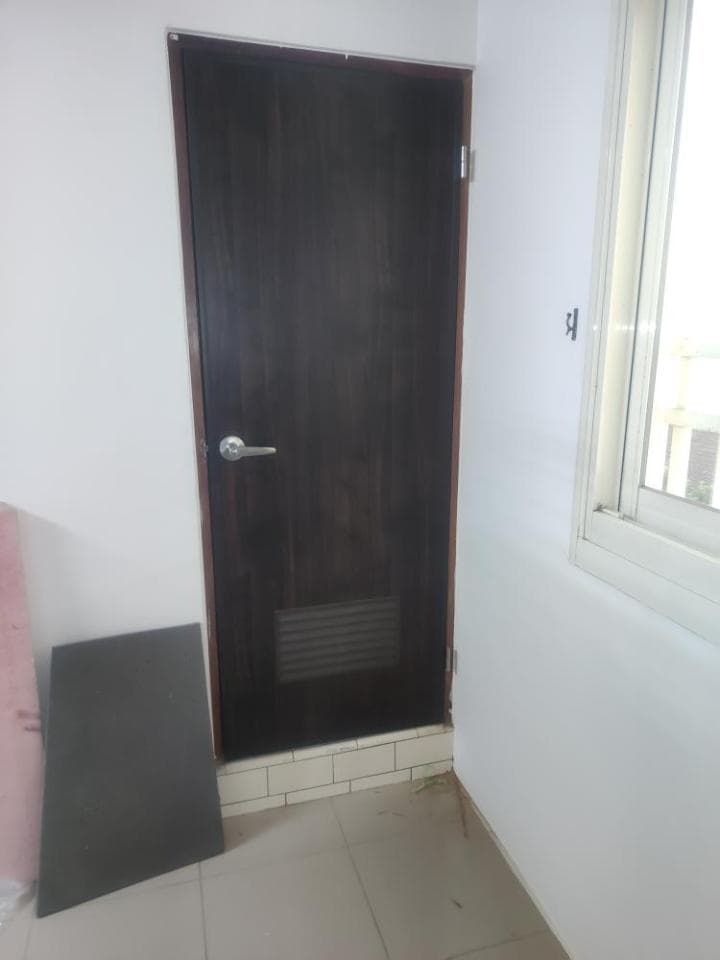 照片中顯示的是一個房間的一部分,房間裡有一個木門,門上有一個銀色的門把