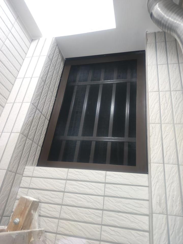 1) 照片中有一個帶有金屬格柵的窗戶,位於一間白色瓷磚牆上