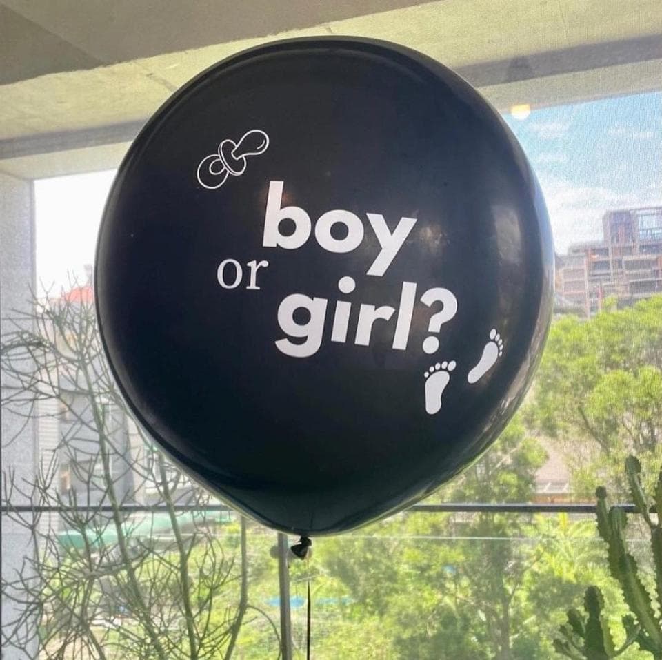 這張「男孩還是女孩」的照片是一個黑色的氣球,上面寫著「男孩還是女孩」,旁邊有奶嘴和腳印的圖案。