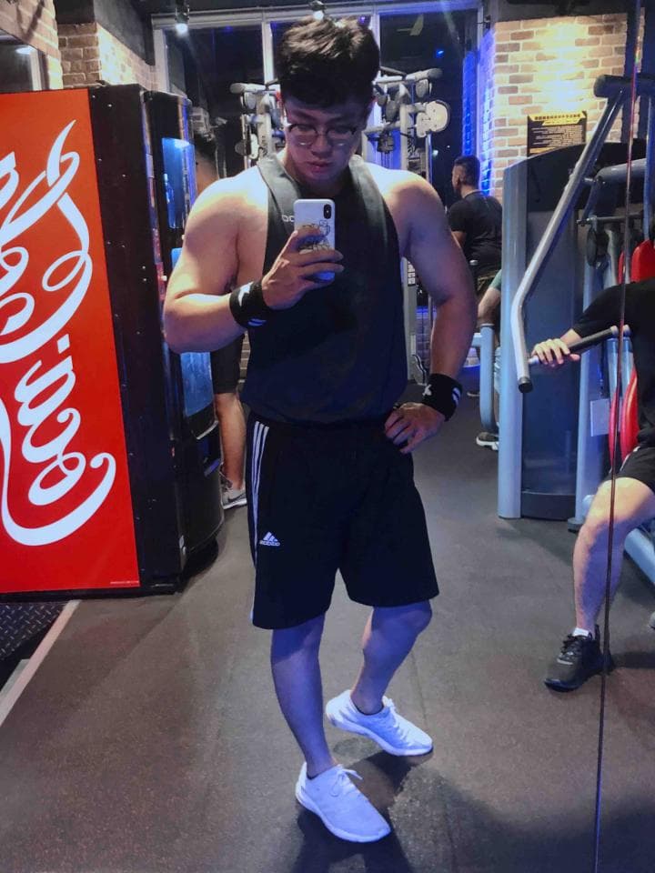 這張「健身房」的照片是一位男子在健身房中,他穿著黑色的運動短褲和白色的運動鞋,正在使用健身器材。