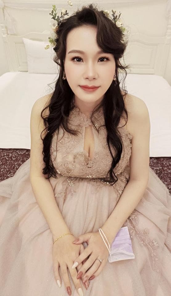 這張照片是一個穿著淺粉色禮服的女孩,她的頭上戴著白色花環,看起來很美麗。