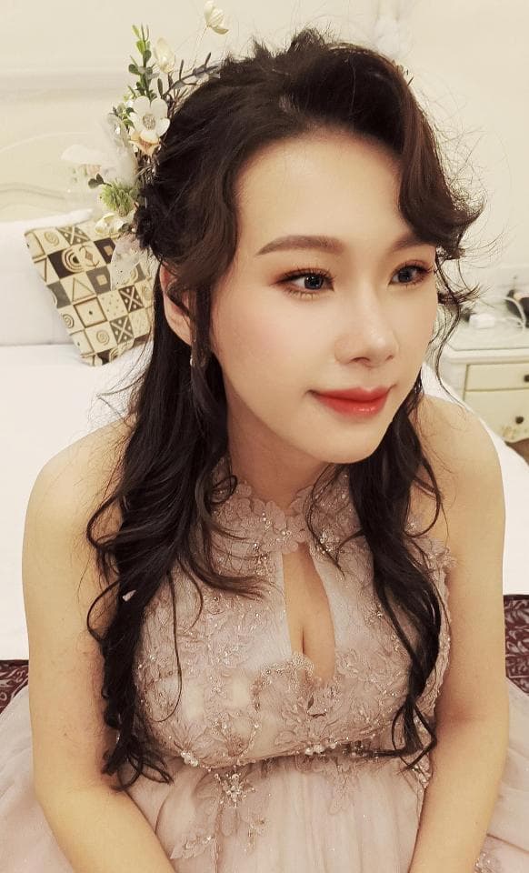 這張照片是一名身穿蕾絲禮服的女性。她留著一頭黑色長髮,並戴著白色頭飾,顯得優雅迷人。